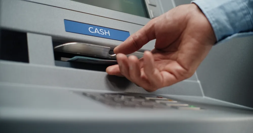 A person using an ATM to withdraw cash.