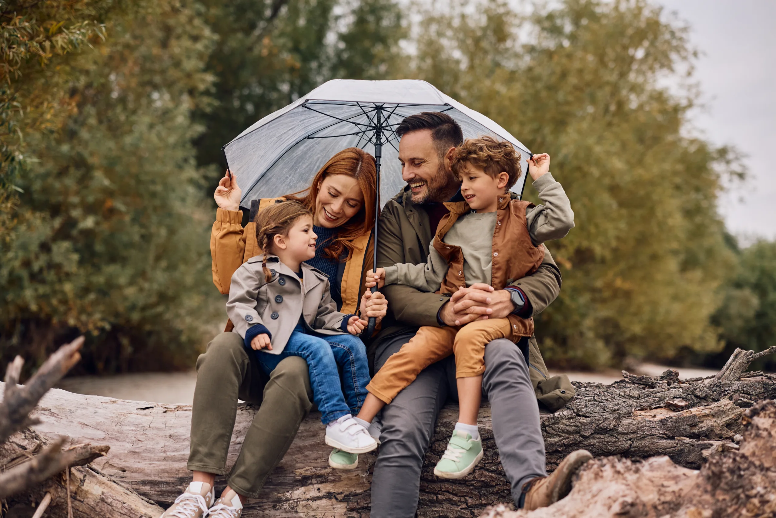 A young family sheltering under an umbrella and smiling